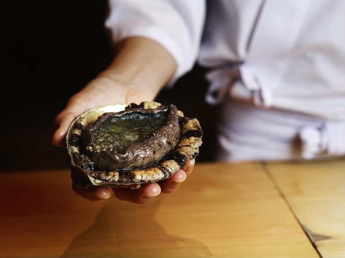 貝を手に持つ料理人